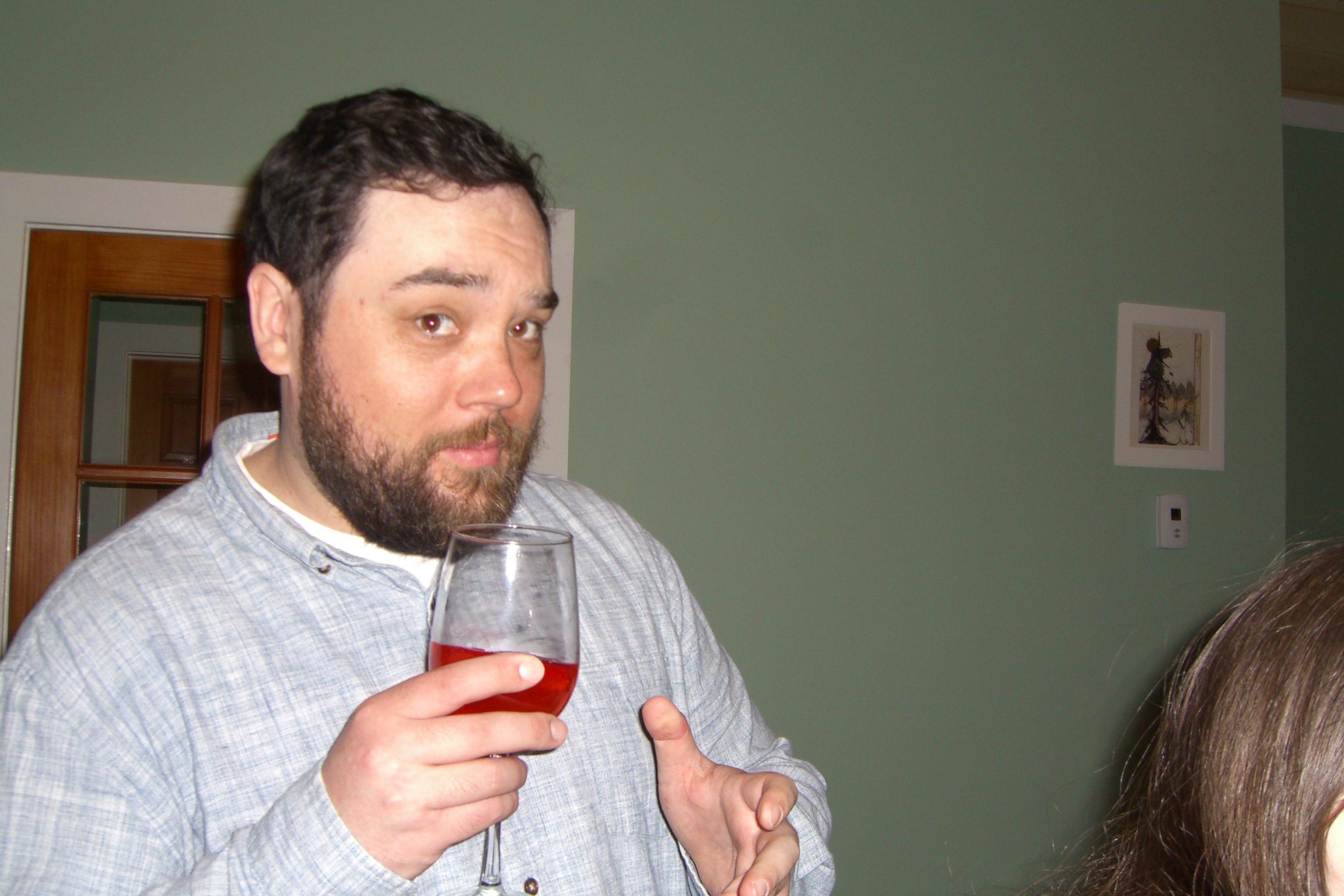 Bearded man holding wine making a funny expression