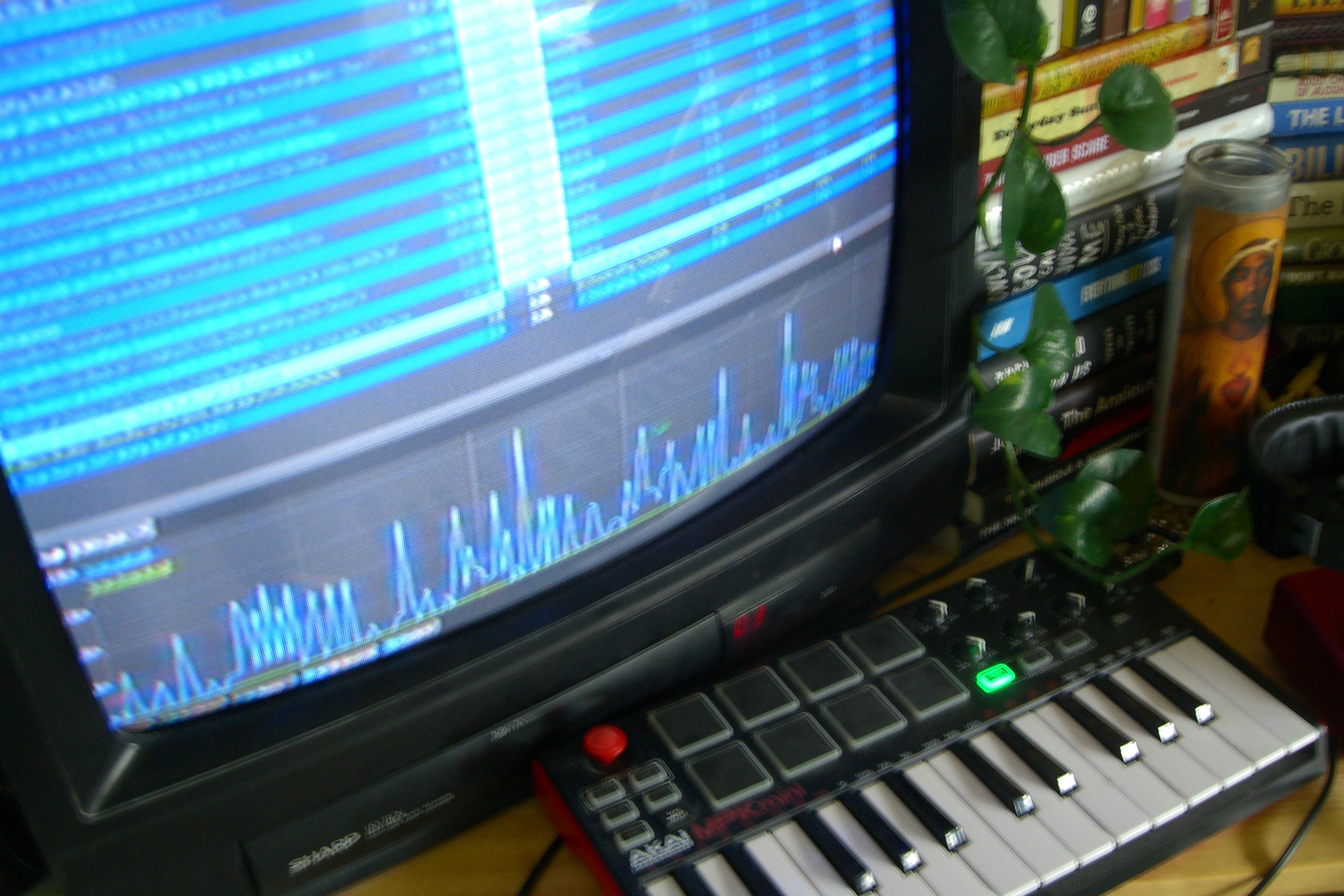 MIDI keyboard and CRT monitor showing a DAW, with books and a plant